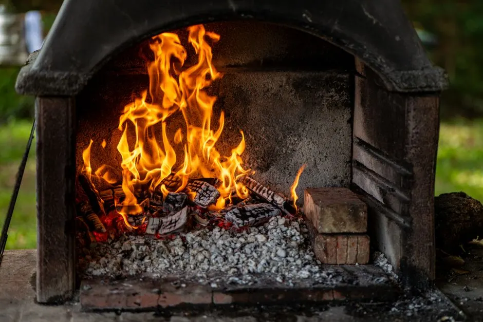 A cozy outdoor fireplace with vibrant flames and burning logs, creating a warm atmosphere.