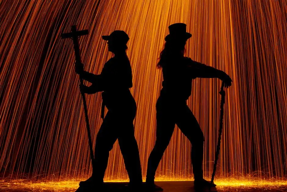 Dynamic silhouettes of performers against a fiery backdrop, captured during a night performance in Tilburg.